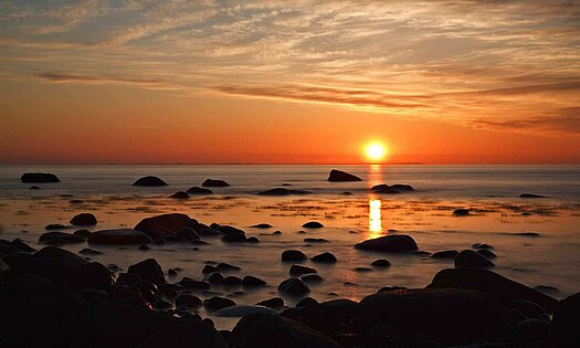 Sonnenuntergang mit Blick auf Meer und Steinstrand