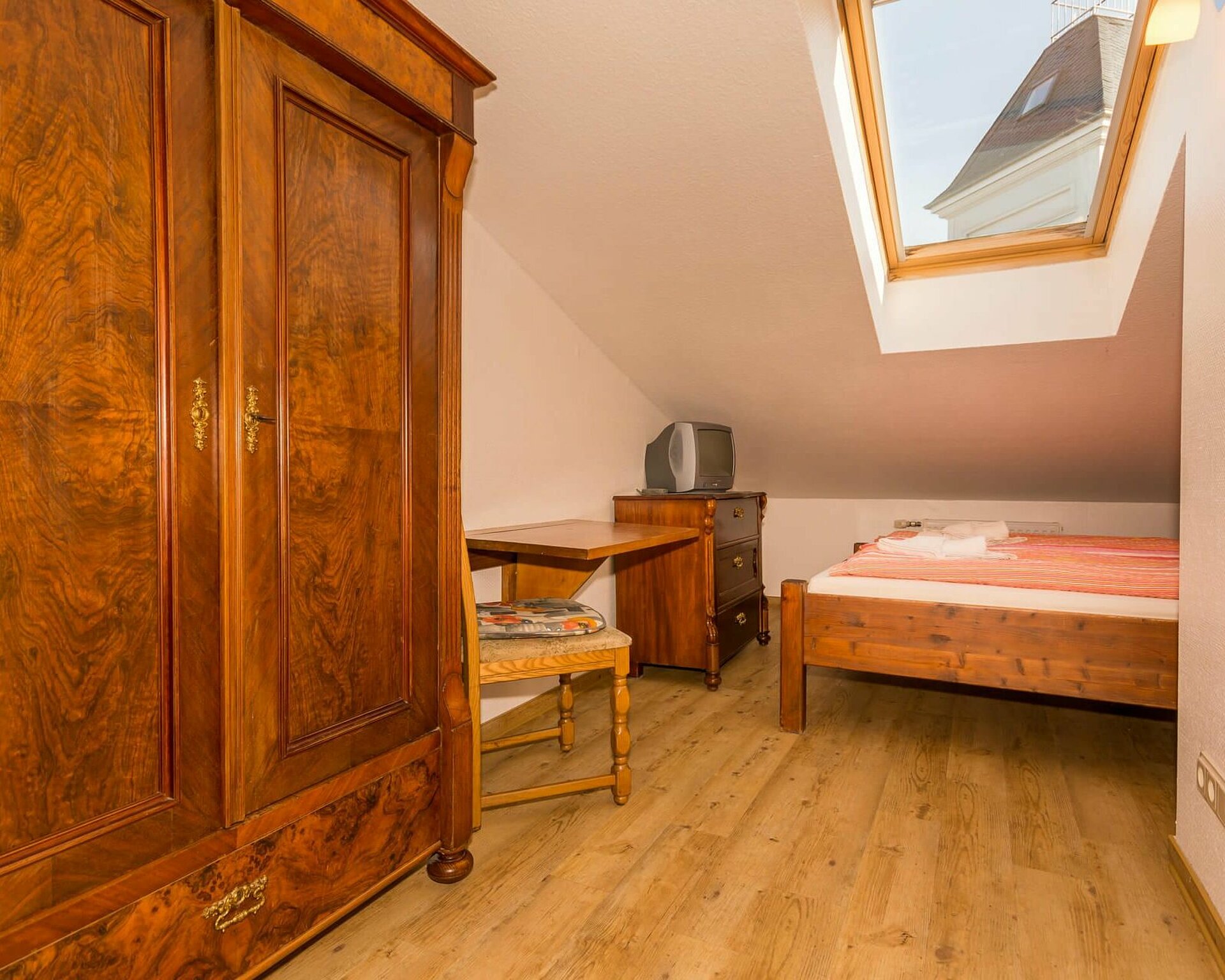 Einzelzimmer mit Bett und kleiner Sitzecke, Kabel-TV in Pension ANKER