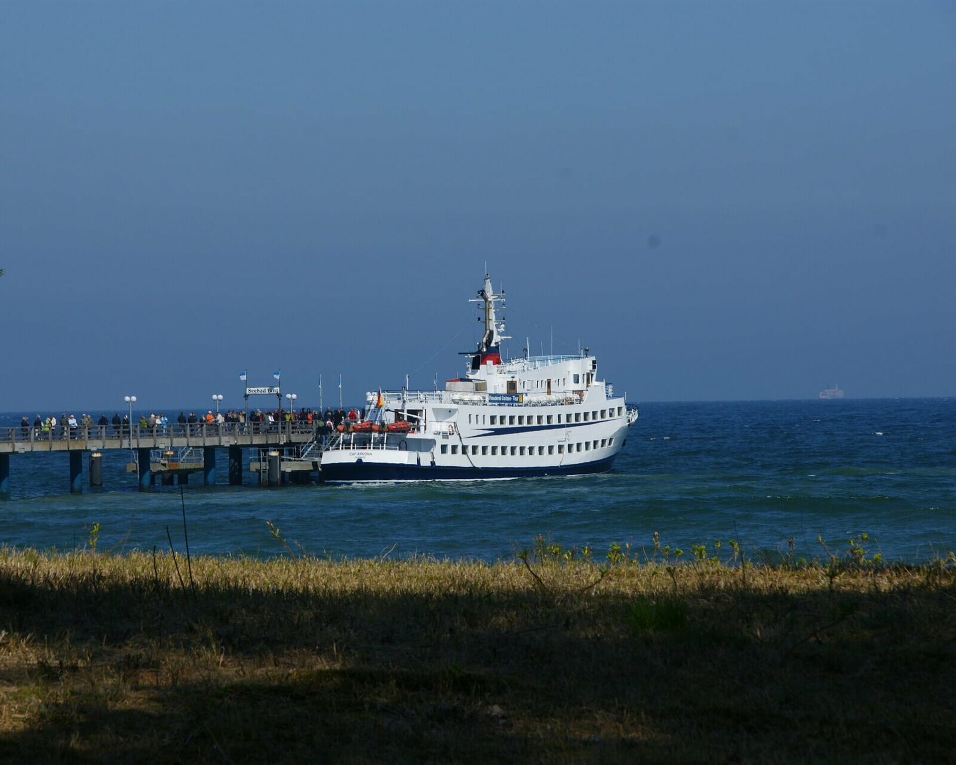 Schiff an der Binzer Seebrücke mit Fahrtgästen von der Strandpromenade