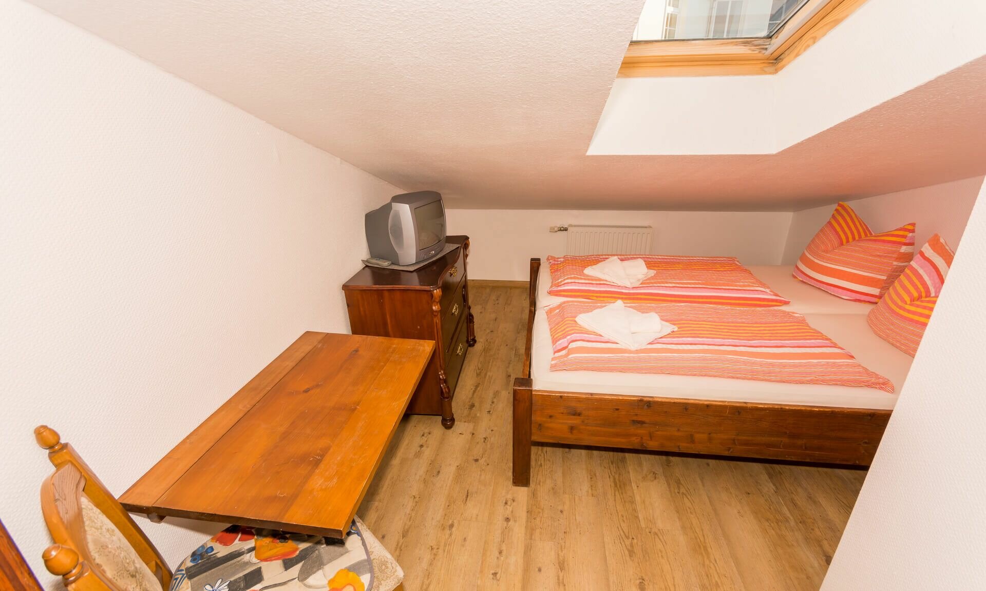 Einzelzimmer im Dachgeschoss mit Bett, kleiner Sitzecke; Kabel-TV